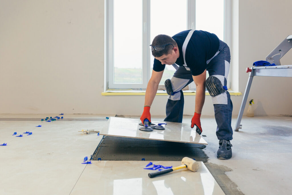 un-constructor-que-instala-el-piso-con-grandes-baldosas-de-ceramica-durante-los-trabajos-de-reparacion